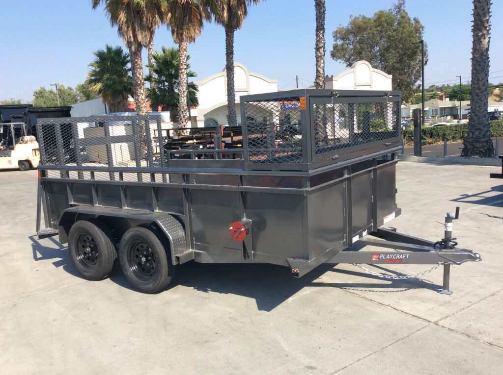 Curbside view of metallic charcoal landscape trailer with 2' solid metal sides, a full-width expanded metal box, weed eater racks, and tool storage