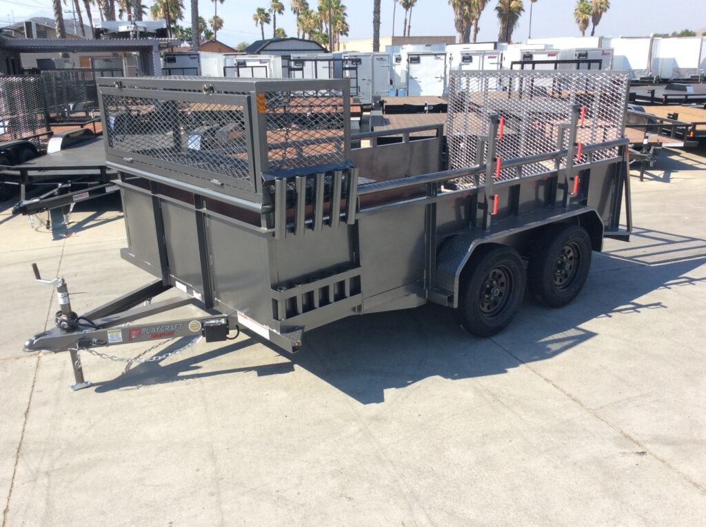 Street-side view of metallic charcoal landscape trailer with 2' solid metal sides, a full-width expanded metal box, weed eater racks, and tool storage